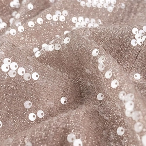 Macro shot of brown mesh fabric with white sequins and soft pleated textures
