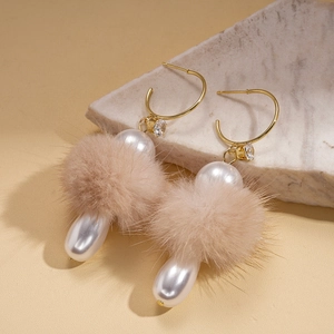 Detail of C-shaped drop earrings featuring fur pom-poms, pearls and crystal accents