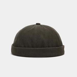 Détail de la texture en velours côtelé vert foncé sur un bonnet docker rétro à bords