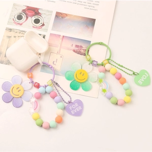 Detail of DIY acrylic beaded keychains with smiley flowers and rainbow charms on pink desk