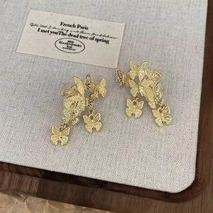 Detailed macro view of retro gold butterfly dangle earrings with intricate 3D layered design