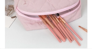 Detailed macro of pink quilted makeup bag with internal slots for cosmetic brushes