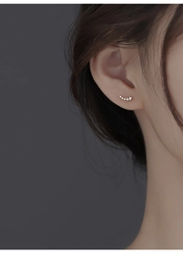 Close-up of minimalist sterling silver curved ear studs with gradient white zirconias