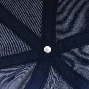 Macro detail of navy denim baseball cap inner seams and silver rivet reinforcement