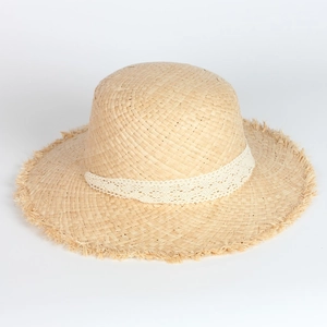 Detail of raffia sun hat featuring wide fringed brim and white lace ribbon decoration