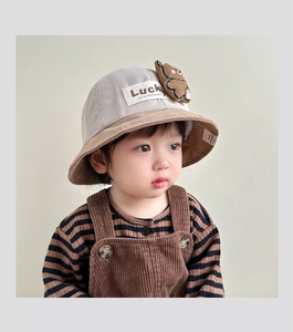 Detail of baby corduroy bucket hat featuring bear accessory and Lucky patch
