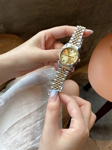 Close-up of women's two-tone stainless steel watch with gold dial and diamond markers