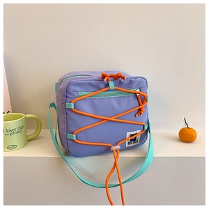 Detail of purple square crossbody bag with orange bungee cords and bear patch label