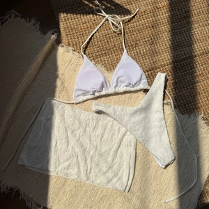 Detailed view of white three-piece bikini set with sheer floral lace cover-up skirt