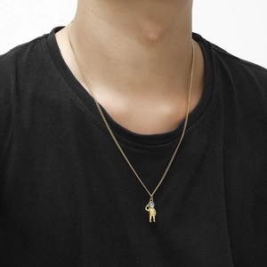 Close-up of gold astronaut pendant with gemstone inlay on a male model wearing a black tee