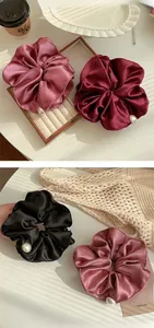 Detailed view of satin scrunchies in pink, burgundy and black with elegant pearl accents
