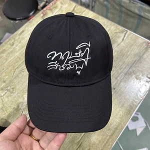 Close-up of black baseball cap with white Thai script embroidery on the front panel