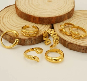 Detailed set of gold plated adjustable rings displayed on a rustic wood slice platform