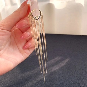 Detail of long gold tassel earrings with triangular studs and cascading metal chains