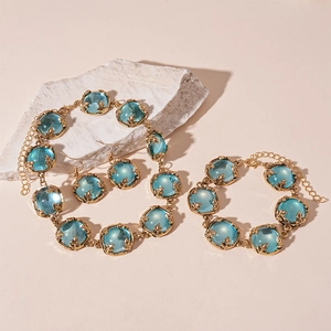 Vintage gold jewelry set with light blue resin stones on a textured stone display
