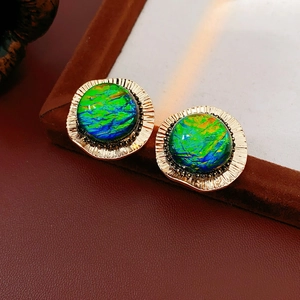 Close-up of vintage round earrings with iridescent resin stones on brown velvet stand
