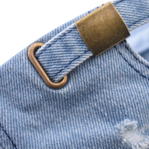 Dettaglio del cappello in denim blu chiaro con fibbia in metallo e trama consumata