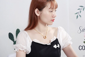 Detail of interlocking gold and silver double ring pendant on woman's neck