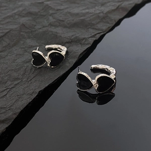 Macro detail of double black heart earrings with textured silver hoop and mirror reflection