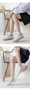 Detail of white cotton socks with colorful floral embroidery and casual sneakers