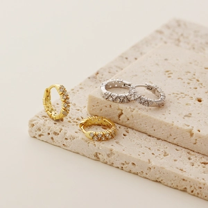 Macro detail of gold and silver S925 double-row pavé diamond hoop earrings on stone