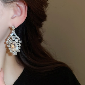 Close-up of elegant silver teardrop earrings with large sparkling rhinestones on model