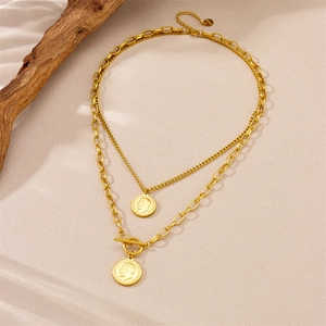 Double-layered gold coin necklace with toggle clasp on a natural driftwood background