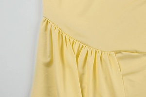 Detail view of ruching design and soft pleated fabric on light yellow dress