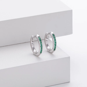 Macro detail of S925 silver hoop earrings with round green zircon stones on white stand