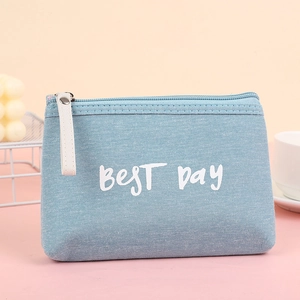 Detail of light blue canvas makeup bag with BEST DAY print and metal zipper on pink desk