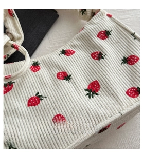Close-up of white corduroy shoulder bag featuring embroidered strawberry patterns