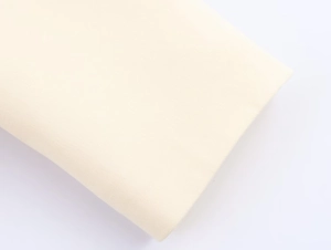 Close-up detail of cream white cotton fabric texture on a long oversized blazer coat