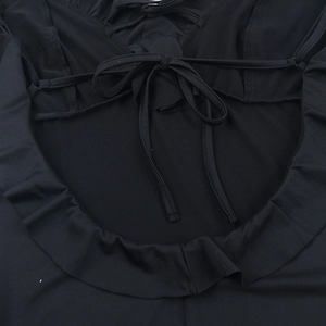 Detail of black off-shoulder dress featuring ruffled edges and criss-cross lace-up design