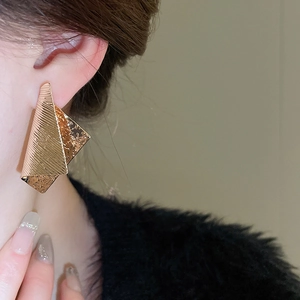 Macro side view of gold irregular geometric earrings with textured brushed finish