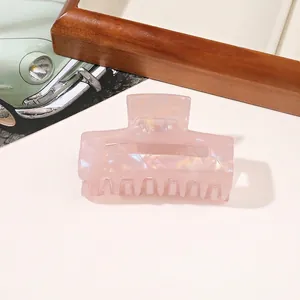 Close-up of pink marble texture hair claw clip with pearlescent finish on desk