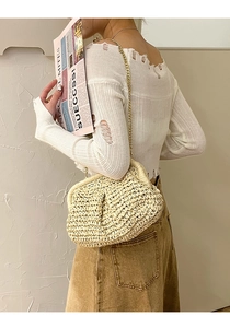 Detail of beige straw clutch with golden chain strap shown on model shoulder