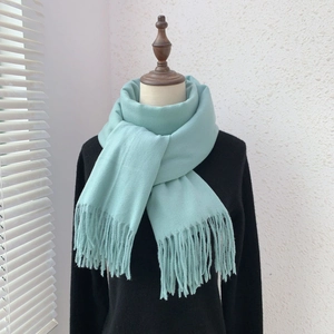 Detail of light blue cashmere-like scarf with soft fringes on a mannequin