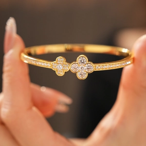 Macro shot of gold clover bangle featuring shimmering zircons on a hand-held display
