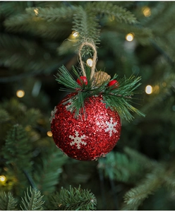 Macro shot of red Christmas ball with silver snowflakes, pine needles and pine cones