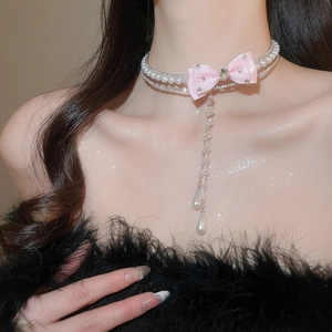 Detail of pearl choker featuring pink silk bow and sparkling rhinestone tassel charms