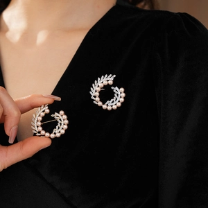 Close-up of gold-plated spiral brooch with pink pearls and zircon on black velvet fabric