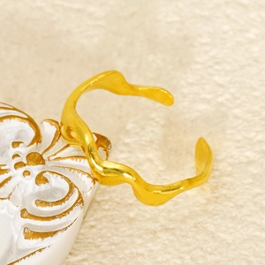 Detail shot of a minimalist gold wavy open bangle with elegant metallic texture
