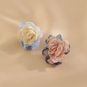Close-up of asymmetric fabric flower earrings in cream blue and dusty pink organza