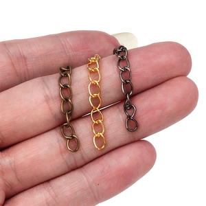 Close-up of DIY jewelry extension chains in gold, bronze and black held for size scaling