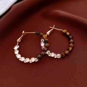 Close-up of 18k gold plated hoop earrings with tiger eye stone and crystal inlay details