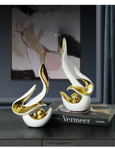 Gros plan de sculptures abstraites en céramique aux accents dorés sur une table