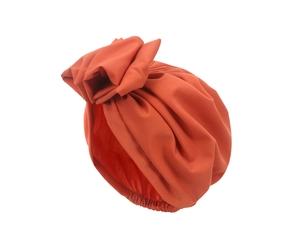 Detailed view of caramel turban hat with large decorative floral knot and elastic pleats