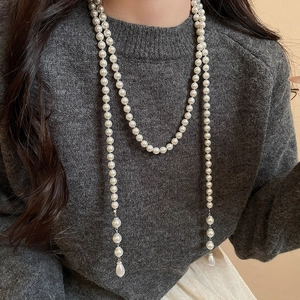 Detail of layered white pearl necklace with a teardrop pearl pendant on a model