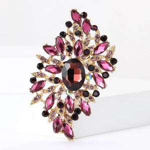 Detailed macro view of gold alloy brooch with large red crystal and purple gemstone accents