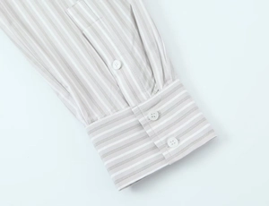 Détail du poignet de chemise à rayures grises avec des boutons en résine blanche